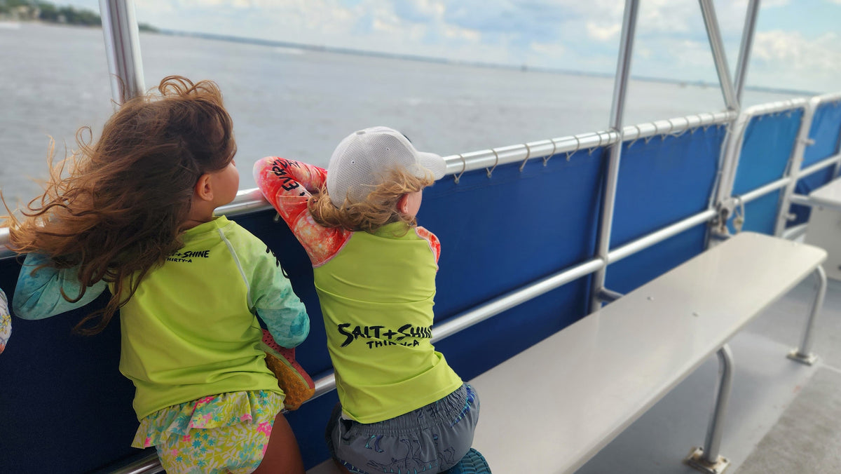 Two kids in Salt + Shine high-visibility UPF 50+ rash guards on a boat, offering sun protection for every water adventure